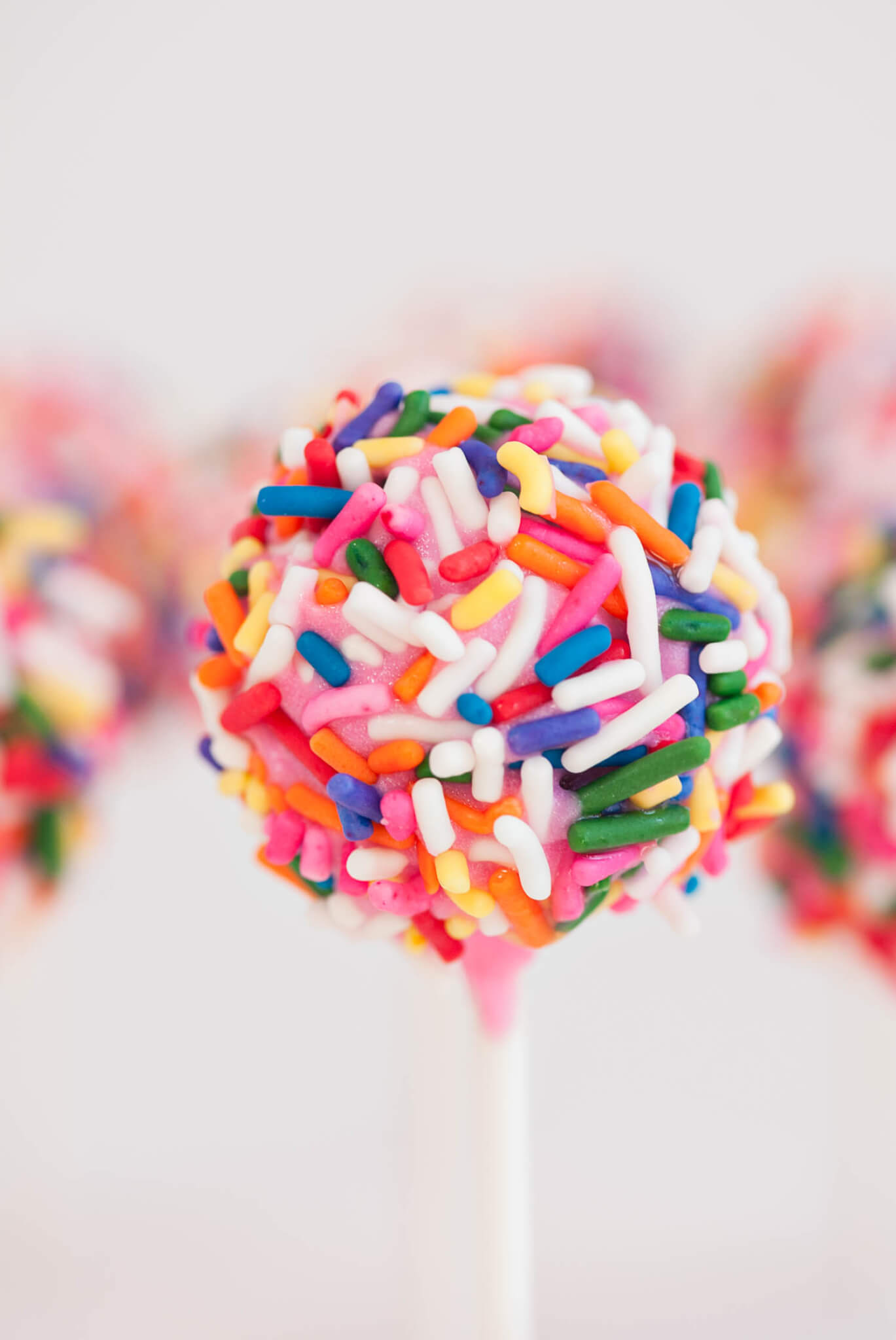 Close up of a Strawberry Confetti Cake Pop covered in Sprinkles